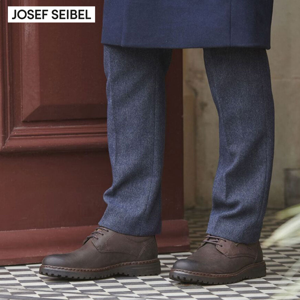 Person wearing brown shoes and blue pants with 'Josef Seibel' branding.