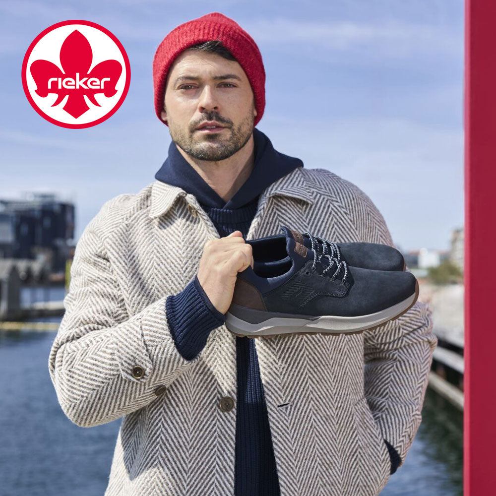 Man holding a shoe with a lake and cityscape in the background, featuring the Rieker logo.