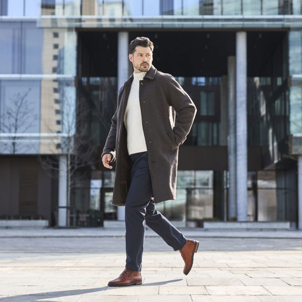 man in coat and brown boots walking