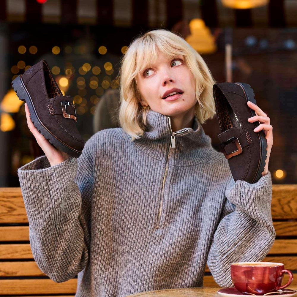 A woman holding up a pair of brown autumn winter shoes